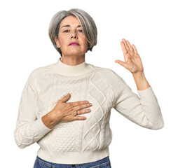 Caucasian mid-age female on studio background taking an oath, putting hand on chest.