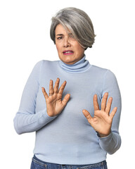 Caucasian mid-age female on studio background rejecting someone showing a gesture of disgust.