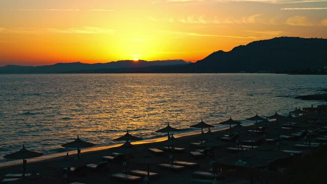 Sandy beach with sun loungers at sunset.