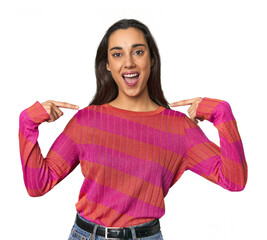 Hispanic young woman surprised pointing with finger, smiling broadly.