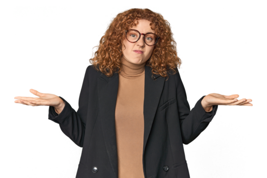Young Caucasian redhead in business attire doubting and shrugging shoulders in questioning gesture.