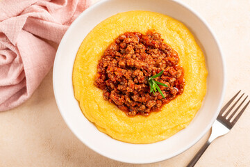 Top view of Polenta with ragu or meat and tomato sauce bolognese. Boiled cornmeal porridge.