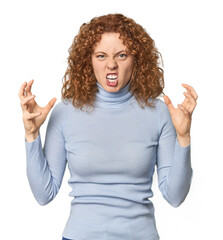 Young Caucasian redhead woman screaming with rage.