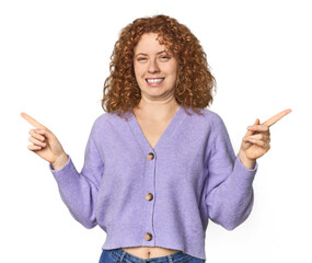 Young Caucasian redhead woman pointing to different copy spaces, choosing one of them, showing with finger.
