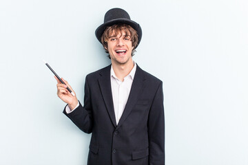 Young magician man holding magic cards isolated on blue background happy, smiling and cheerful.