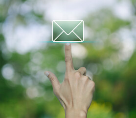 Hand pressing email flat icon over blur green tree in park, Business contact us online concept