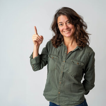femme souriante de face en chemise casual montrant le haut avec son doigt