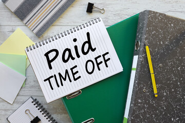 PAID TIME OFF text on a notebook on a green folder