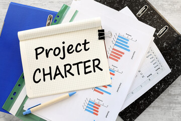 PROJECT CHARTER work desk blue folder blue financial charts. text on a notebook