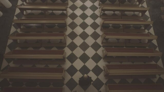 Christian monks walking through wooden pews row aisle to altar in church top view. Priests wearing robes praying in catholic temple. Christianity concept