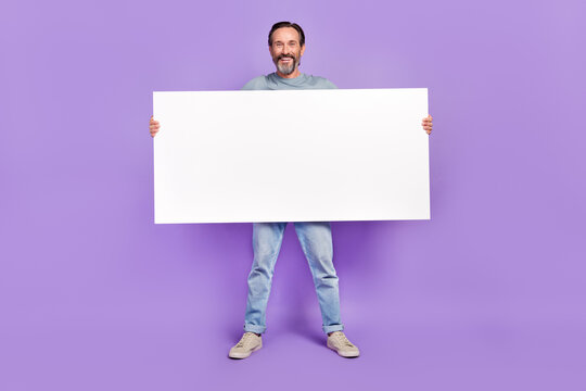 Fototapeta Full body photo of aged man hold big paper white banner promotion isolated over violet color background