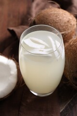 Glass of coconut water and nuts on wooden table