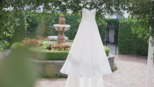 Wedding dress hangs in front of fountain