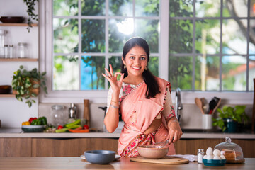 Portrait of happy Indian asian young woman wears saree while working in kitchen