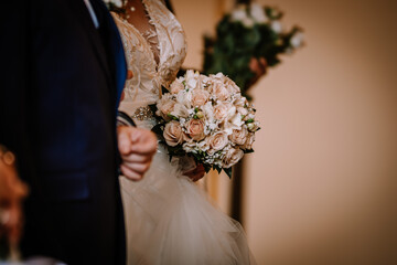 Valmiera, Latvia - August 5, 2023 - Close-up of a bride holding a bouquet of roses, partial view of...