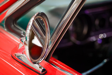 Side view of a vintage car's rearview mirror. Red colored car. Classic vehicle. 