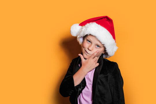 Thoughtful child with Santa hat posing in studio