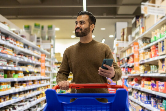 Man shopping with smartphone in grocery aisle