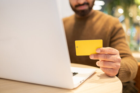 Man holding a credit card while using a laptop