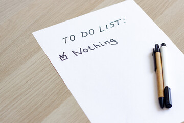 A white blank note or sheet of paper is on a wooden table background. To do list concept with no...