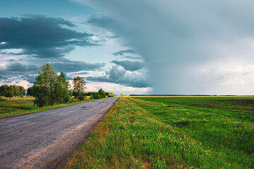 thunderstorm and heavy rain in a field above the road at a beautiful sunset in the summer, the problem of a slippery road