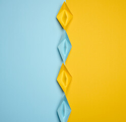 Paper boats on a yellow background, top view, representing the concept of unity and achieving...