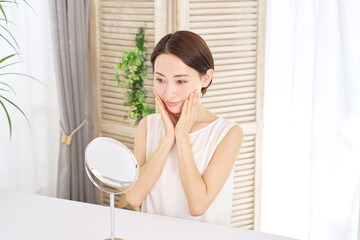 自宅でフェイシャルケアをする中年女性