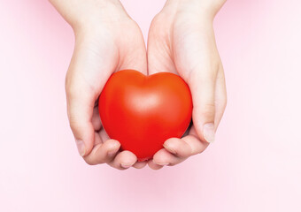 Children's hands holding a red heart as a simbol of care, love, support and protection