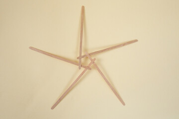 Bamboo wooden sticks demonstrating a pentagram reciprocal frame structure, on beige background