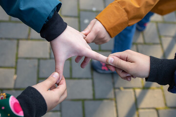 Four hands pulling fingers, children playing in the park