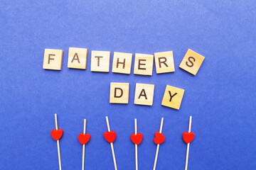 Father's day word made by wooden cubes. Red hearts on a blue background.