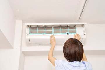 エアコンのフィルターを掃除する女性