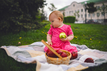 Young Girl in a Pink Dress Enjoying an Apple on a cloudy Day at the Park
