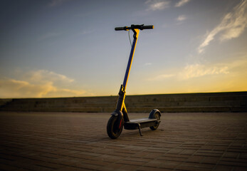 Electric Scooter Standing Alone a Calm Evening. A solitary electric scooter is captured as dusk settles, casting a warm glow.