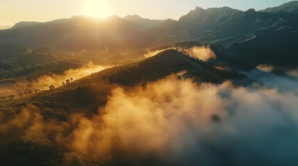 Aerial view of a mountain range with sunlight breaking through clouds in the sky