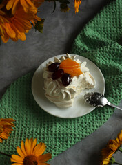 Meringue dessert by Anna Pavlova with fruits on a plate with Jerusalem artichoke flowers