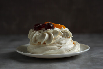 Meringue dessert Anna Pavlova with fruits on plate on dark background