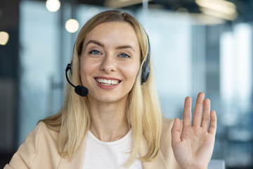 Friendly businesswoman waving during a video call with headset
