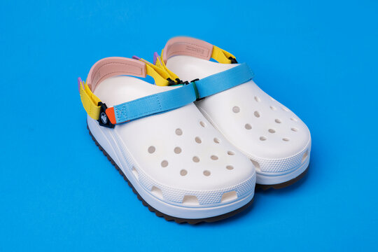White rubber sandals from Crocs with straps isolated on the blue background