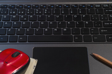 computer keyboard or notebook, with a red mouse and notepad with pencil, work at home concept