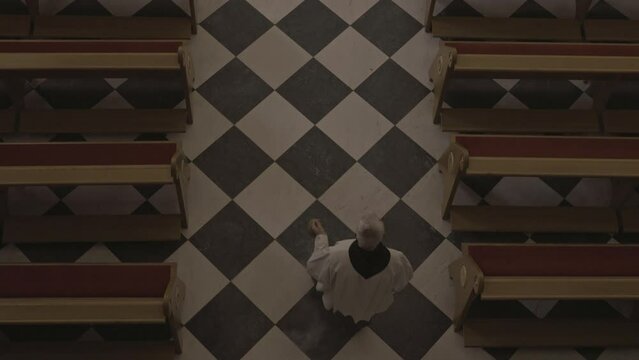 Priests walking in white robes during liturgy along christian cathedral aisle top view. Catholic Ministers carrying thurible in church. Sacred mass ceremony concept