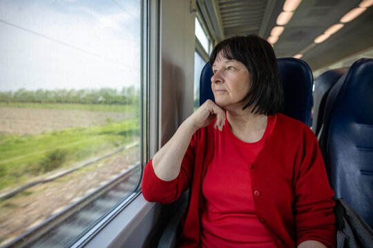 Elderly woman travelling solo by train, looking through out the window