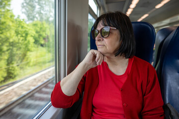 Elderly woman travelling solo by train, looking through out the window