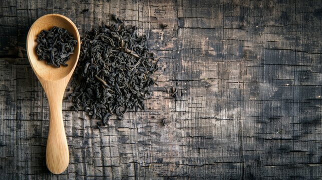 Wooden spoon with black tea near tea pile