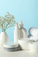 Different bath accessories and gypsophila on white table against light blue background