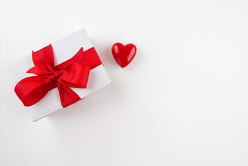 Top view photo of white gift box with red heart and bow with red ribbon on isolated white background