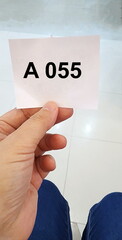 Hold queue card number A 055 with numbers printed in black on white paper. paper queue from the...