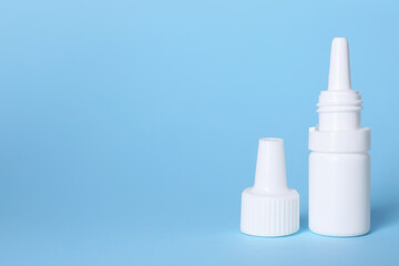 Bottle of medical drops on light blue background, space for text