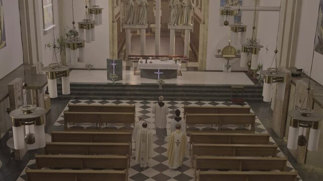 Christian priests walking to altar in cathedral during Holy Mass top view wide shot. Sacred religious liturgy ceremony in church. Procession of Ministers concept