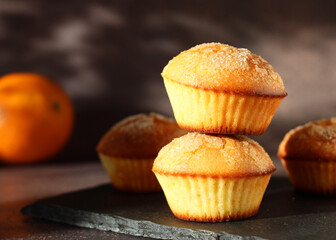 Dessert orange muffins in rows on dark background with orange